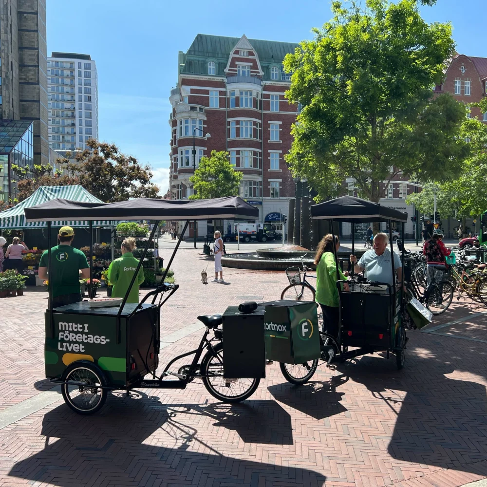 Eventpersonal med profilklädda cyklar genomför utomhuskampanj för Fortnox i citymiljö.